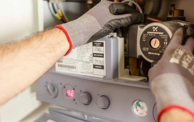 Chauffagiste en train de dépanner un chauffe-eau gaz instantané